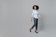 © ViDi Studio - Full body side view smiling fun young employee business corporate lawyer woman of African American ethnicity in classic formal shirt work in office walking go look aside isolated on grey background.