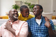 © wavebreak3 - Happy african american boy with father and grandfather sitting on sofa at home