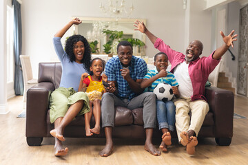 Wall Mural - African american multi-generational family cheering while watching soccer match on tv