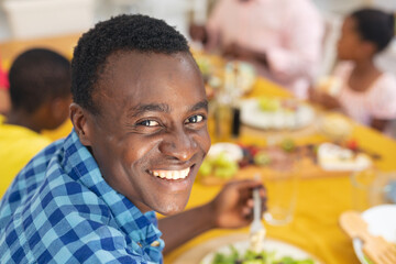 portrait of smiling african american mid adult man having lunch with family on thanksgiving day