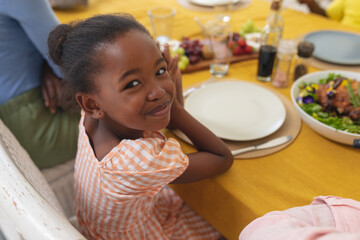 African american smiling girl having lunch with family at dining table on thanksgiving day