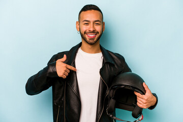 Wall Mural - Young hispanic biker man isolated on blue background person pointing by hand to a shirt copy space, proud and confident