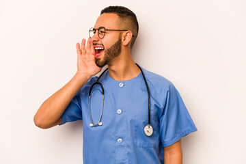 Wall Mural - Young hispanic nurse man isolated on white background shouting and holding palm near opened mouth.