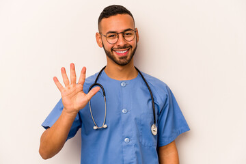 Wall Mural - Young hispanic nurse man isolated on white background smiling cheerful showing number five with fingers.