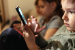 © Jelena Stanojkovic - Close up of a line of small group of kids using mobile phones at home. Group of children sitting in a row and typing a message on smartphone. Young boys and girls playing with cellphone.