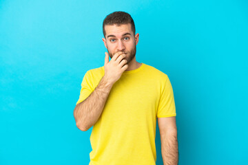 Wall Mural - Young handsome caucasian man isolated on blue background surprised and shocked while looking right