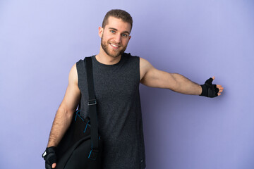 Canvas Print - Young sport man with sport bag isolated on white background extending hands to the side for inviting to come