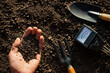 The fertile loam soil was in the hands of the man and the farming equipment was placed in it.