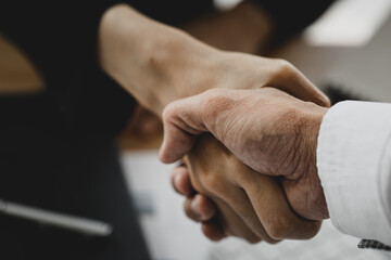 Close-up two business men holding hands, Two businessmen are agreeing on business together and shaking hands after a successful negotiation. Handshaking is a Western greeting or congratulation.