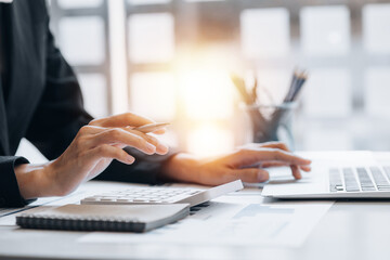business woman using a calculator to calculate numbers on a company's financial documents, he is ana