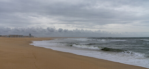 Poster - empty beach with waves crashing on golden sand on an overcast day in Figueira da Foz