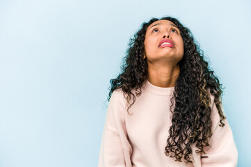 Wall Mural - Young hispanic woman isolated on blue background shouting very angry, rage concept, frustrated.