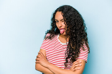 Wall Mural - Young hispanic woman isolated on blue background funny and friendly sticking out tongue.