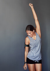 Wall Mural - Getting back into her exercise routine. Studio shot of a sporty young woman looking excited against a gray background.