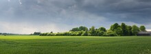 Green Hills Of A Plowed Agricultural Field And Forest. Idyllic Summer Rural Scene. Dramatic Sky, Rain, Thunderstorm. Pure Nature, Environnement, Farm, Countryside Living, Ecotourism. Panoramic View