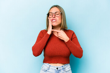 Wall Mural - Young caucasian woman isolated on blue background having a strong teeth pain, molar ache.