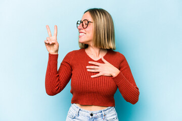 Wall Mural - Young caucasian woman isolated on blue background taking an oath, putting hand on chest.