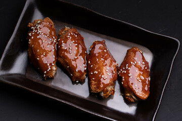Wall Mural - Fried chicken wings with spicy and sweet Korean sauce topped with white sesame seeds
