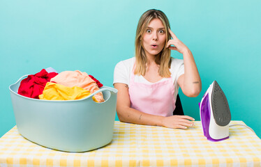 pretty blonde woman looking surprised, realizing a new thought, idea or concept. iron and clothes concept