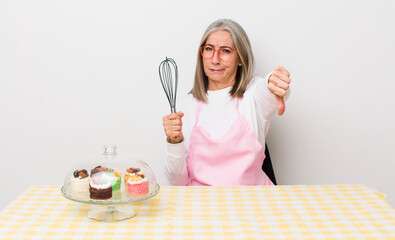 Wall Mural - senior  gray hair woman feeling cross,showing thumbs down. homemade cakes concept