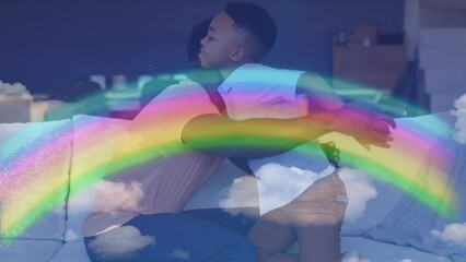 Poster - Animation of rainbow over happy african american father and son hugging on sofa