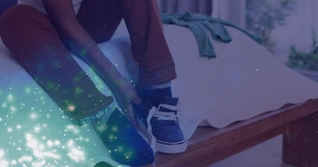 Poster - Animation of lights over feet of african american boy tying shoe on bed