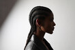 Side portrait of African young woman with braids posing on white wall. 