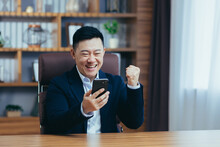 Young Handsome Happy Asian Businessman Man Rejoices, Got Good News, Uses Phone. Concluded An Agreement, Received A Contract