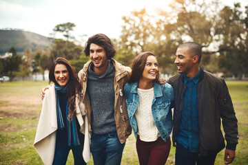 Aufkleber - Where are we going to now. Portrait of a group of cheerful young friends huddled together while walking in a park outside during the day.
