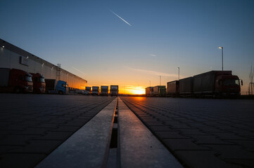 logistics area with halls and trucks at sunset. transport and storage of goods.