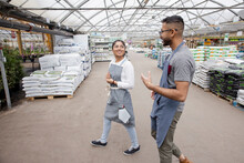 Cheerful Workers Walking Together In Garden Center