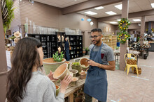 Store Worker Assisting Customer With Plant Pot In Garden Center