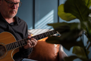 Wall Mural - Man playing guitar at home in natural light