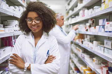 Poster - We have what you need right here. Portrait of a cheerful young female pharmacist standing with arms folded while looking at the camera in a pharmacy.