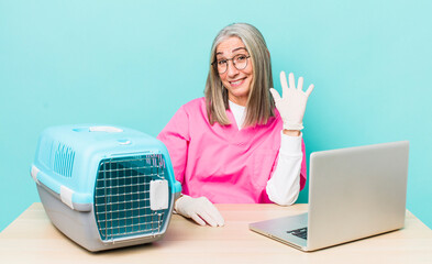 Wall Mural - senior gray hair woman smiling happily, waving hand, welcoming and greeting you. veterinarian concept