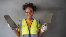Portrait Of An Attractive African-American Woman Standing With Plastering Tool. The Back Is Grey Cement Wall.
Female Worker,wall Decoration Specialist.Smiling Confidently.
Expert Skim Coat,plastering