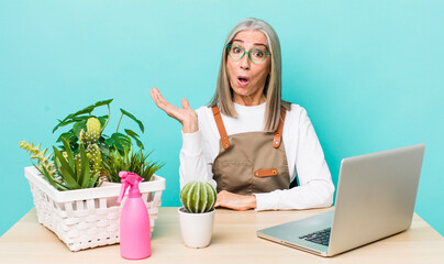 Wall Mural - senior gray hair woman looking surprised and shocked, with jaw dropped holding an object. gardener and plants concept