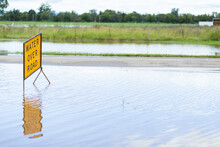 Floodwater Rising Over Water Over Road Sign On Highway