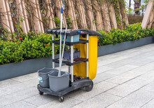 Cleaner Cart In A Public Place With Cleaning Products: Mop, Buckets For Cleaning The Floor, Broom Scoop, Household Chemicals, Household Rags