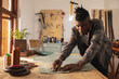 © Wavebreak Media - African american young craftsman cutting leather with equipment and ruler at workbench in workshop