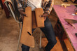 © Wavebreak Media - Midsection of african american young craftsman holding leather while sitting on chair in workshop