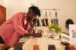 © Wavebreak Media - Smiling young african american male owner writing on book during phone call in leather store