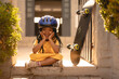 © Wavebreak Media - Portrait of cheerful african american girl wearing helmet sitting cross-legged by skateboard at gate