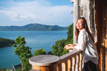 Portrait image of a young asian woman looking at a beautiful sea view from resort terrace