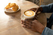 © Wavebreak Media - Hands of african american male customer holding coffee mug by croissants at table in cafe