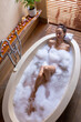 © Wavebreak Media - High angle view of sensual biracial young woman with eyes closed relaxing in soapy bathtub at spa