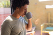© Wavebreak Media - Close-up of african american young man drinking coffee while standing by window at home