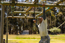 African American Male Soldier Climbing Monkey Bars During Obstacle Course At Boot Camp