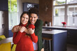 © Wavebreak Media - Portrait of happy young biracial man embracing girlfriend from behind standing in kitchen at home