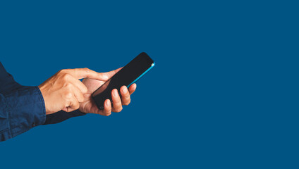 Wall Mural - close-up of hands using a mobile phone while standing over a blue background